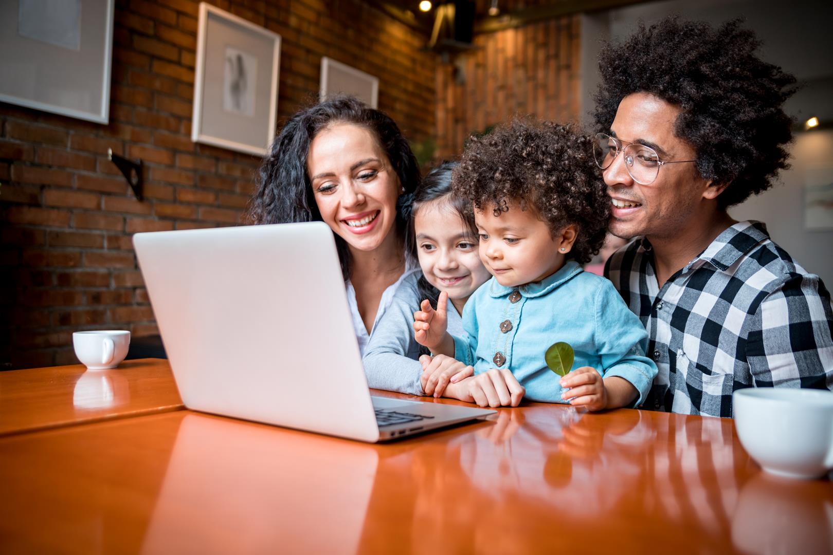 Happy multiethnic family having fun while using laptop together